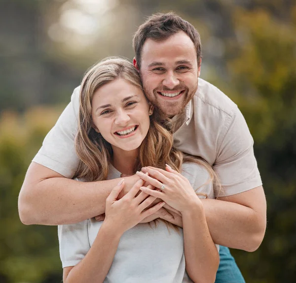 Portrait of loving young caucasian couple spending time together outdoors on a sunny day. Handsome smiling man holding and embracing his beautiful wife while bonding at the park