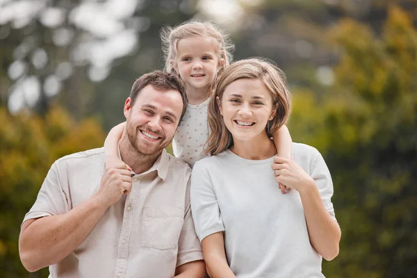 Portrait of a happy young couple bonding with their daughter in the garden at home during the weekend. Adorable little girl hugging her mother and father in a backyard. Showing love, affection, trust.