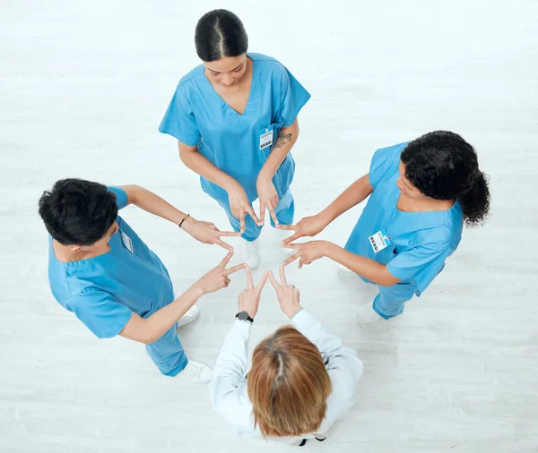 Above shot of a group of medical practitioners joining their hands in a star shape together at a hospital.