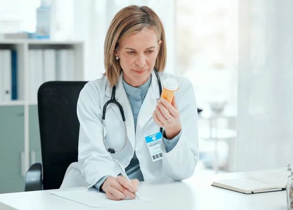 Shot Mature Doctor Sitting Alone Her Clinic Writing Notes While — Foto Stock