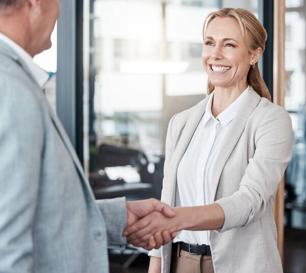 Shot of two businesspeople shaking hands in an office at work.