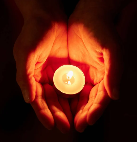 Shot of a unrecognizable person holding a candle in the dark.