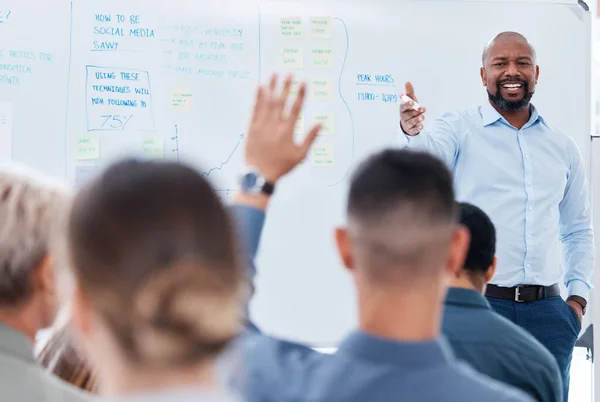 Mature african american business manager training and teaching team of colleagues in office. Black businessman using a whiteboard to talk and explain to diverse group of business people in workshop.