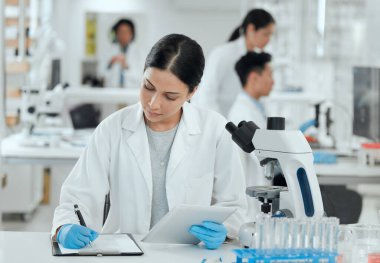 Shot of a young woman making notes in her lab.