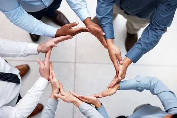 Shot of a group of unrecognizable businesspeople forming a circle with their hands outside.