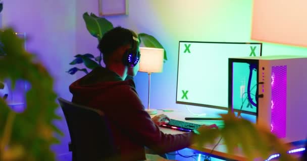 Fiatal Srác Videojátékozik Egy Számítógépen Zöld Képernyővel Neonfényekkel Éjszaka Visszapillantás — Stock videók
