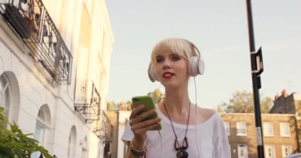 Video Footage Young Woman Wearing Headphones Using Cellphone While Walking — Stockvideo