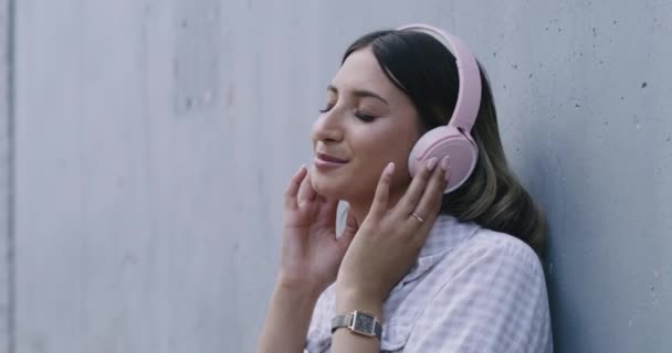 Wanita Mendengarkan Musik Dengan Headphone Bluetooth Bersandar Dinding Beton Luar — Stok Video