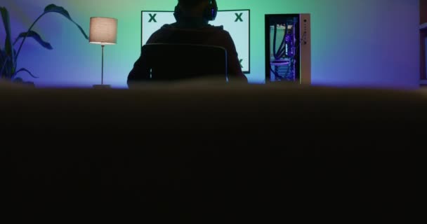 헤드폰을 게임을 컴퓨터 게이머의 뒷모습 어두운 데스크 모니터를 사용하여 포트와 — 비디오
