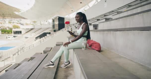 African Female Athlete Checking Notifications Her Phone While Sitting Stadium — Stockvideo