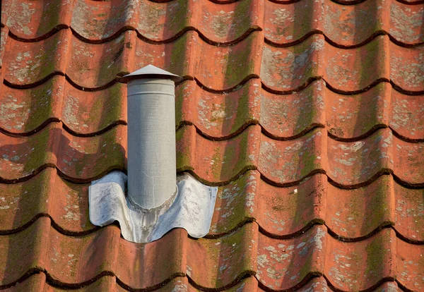 Air flow ventilation pillar and chimney on a slate roof of q house or factory building outside with copyspace. Construction of an exterior vent on rooftop for fireplace or oven smoke and heat control.