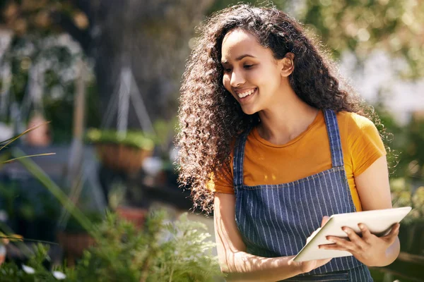 a young female florist taking notes while examining plants at work.