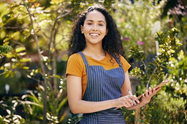 a young female florist taking notes while examining plants at work.