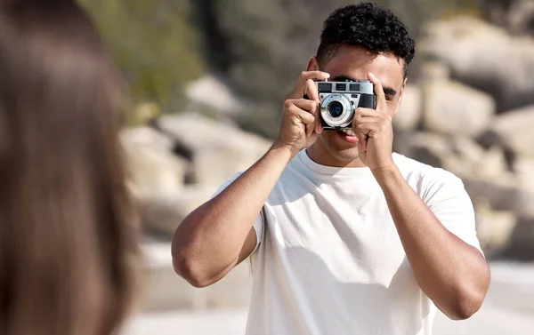 a young man taking pictures of his girlfriend at the beach.