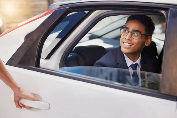 a handsome young businessman sitting in the backseat of a taxi.