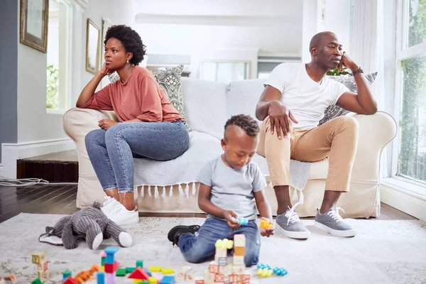 a little boy playing with his toys while his parents sit in the background.