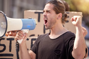 a young man using a megaphone at a protest rally.