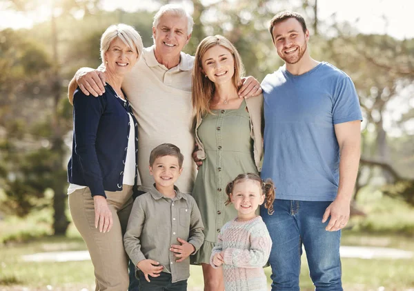 Portrait of a smiling multi generation caucasian family standing close together outdoors. Happy adorable sibling brother and sister bonding with their mother, father, grandfather and grandmother at a