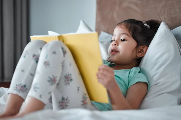 Mała Dziewczynka Czytająca Książkę Leżąc Łóżku — Zdjęcie stockowe