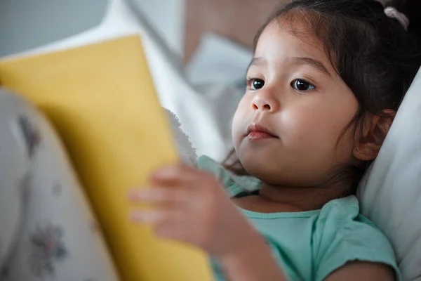 Little Girl Reading Book While Lying Her Bed — Stockfoto