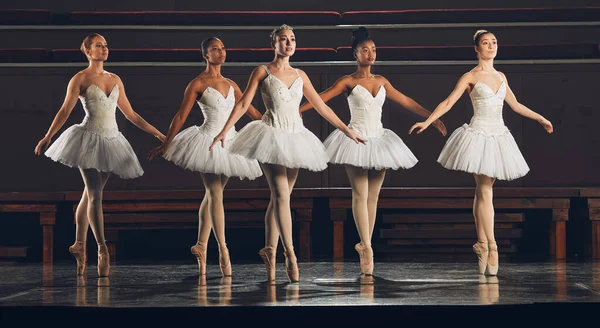a group of ballet dancers practicing a routine on a stage.
