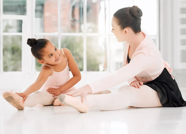 a ballet teacher and student taking a break and talking on the floor of a dance studio.