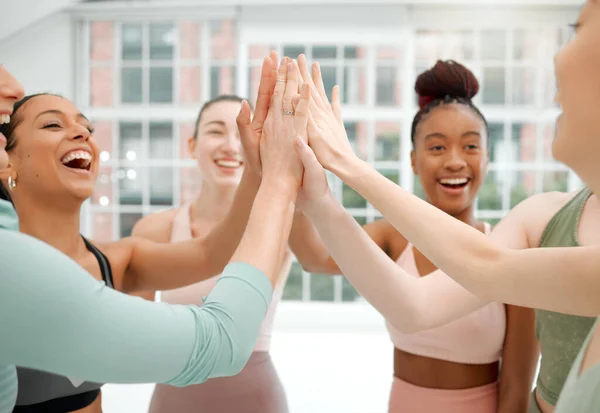 a group of fit young women sharing a high-five.