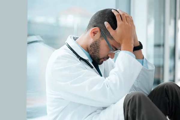 a young male doctor looking stressed out while at work at a hospital.
