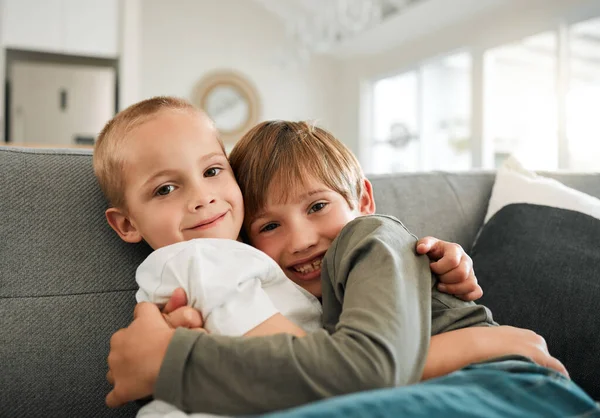 two little brothers hugging each other on the couch at home.