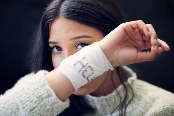 a young woman with bandages wrapped around her wrists showing help written on them.