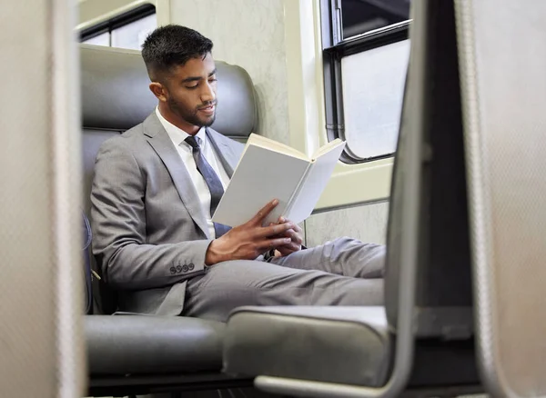 a young businessman reading a book in a train during his commute.