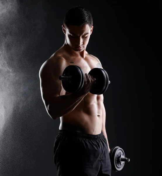 Een Atletische Man Tilt Halters Tegen Een Donkere Achtergrond — Stockfoto