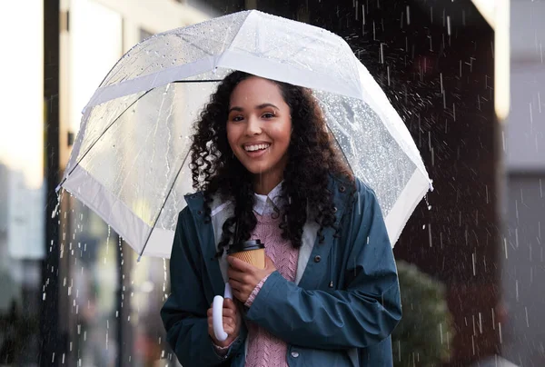 a young woman holding an umbrella and coffee cup in the city.