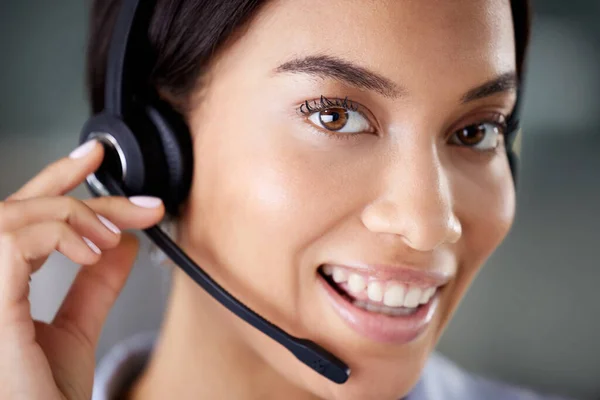 an attractive young call centre agent wearing a headset in the office during the day.