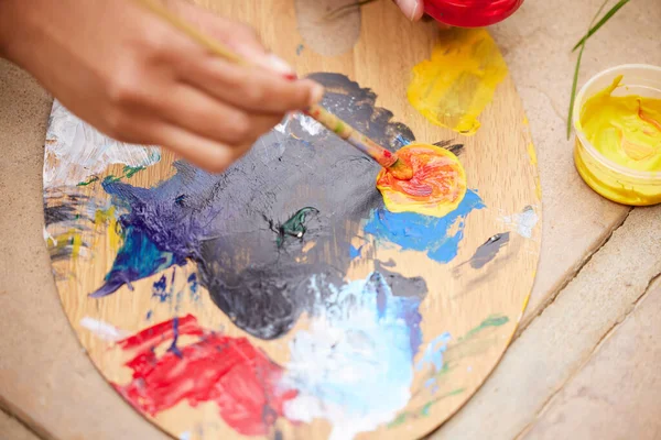 s unrecognizable woman painting a pot in the garden at home.