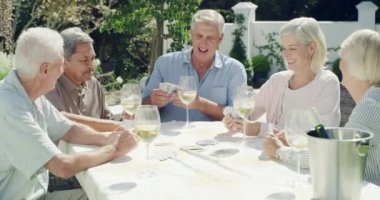 4k video footage of a group of friends playing card games while enjoying some wine during lunch.
