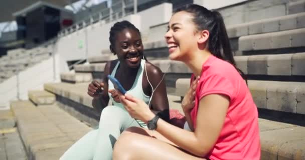 Dos Mujeres Deportistas Escuchando Música Través Auriculares Sentadas Escaleras Afuera — Vídeo de stock