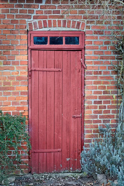 An old, large, red wooden door in a face brick building, most likely a house in a residential district. The entrance way to a house or home. When opportunity knocks, you answer. A vintage residence.