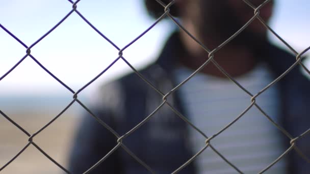 Closeup Man Resting Hand Chain Link Fence Blurry Urban Background — Wideo stockowe