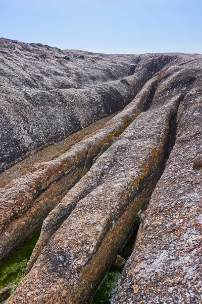 Closeup of rough sea rock with deep cracks, crevices from ocean water erosion, global warming or climate change on beach. Texture detail of sedimentary rock acting as wave breaker on coastal seaside.