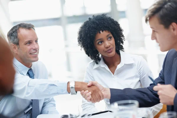 Two businessmen shaking hands in agreement during a meeting.