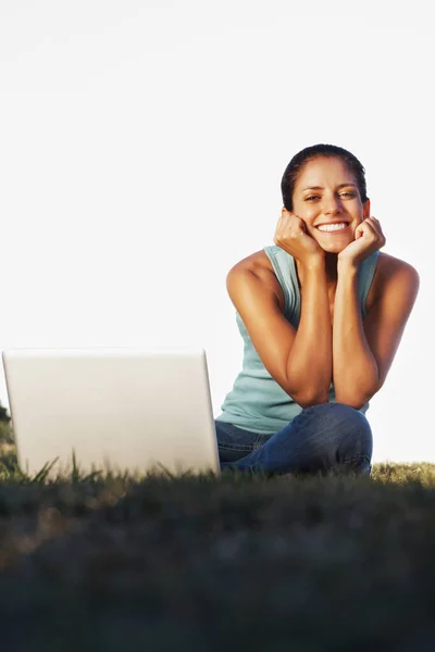 Portrait of beautiful woman sitting outdoors with laptop and giving you a smile.