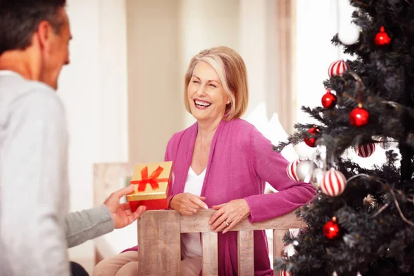 Portrait of a mature man giving gift to cheerful wife on Christmas festival.