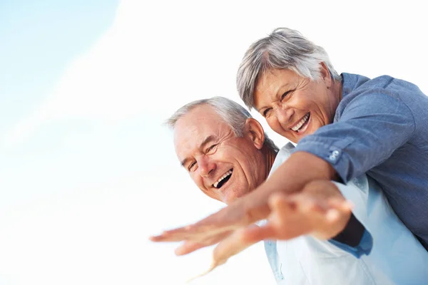 Cheerful Man Piggybacking Mature Woman Outdoors Hands Outstretched — Stockfoto