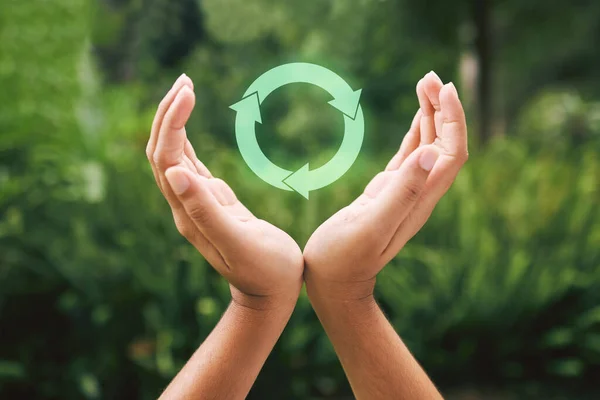 Hands supporting a digital recycle symbol. Someone protecting the environment through recycling. Technology is the future of sustainability.