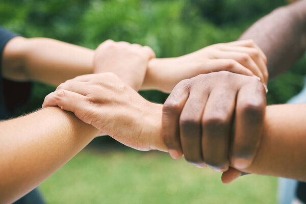 Hands holding wrists outside in nature. A diverse group of people holding wrist as a concept of loyalty. Closeup of a multiethnic group holding wrists.