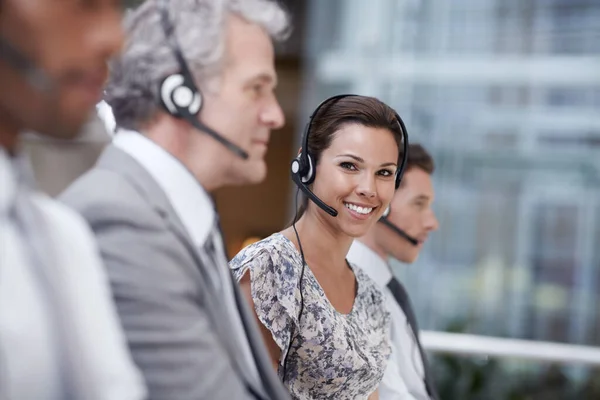 Portrait of an attractive customer service representative talking into a headset while smiling at the camera.