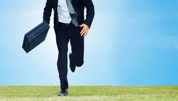 Cropped image of a male business executive running with a briefcase on a field - Copyspace.