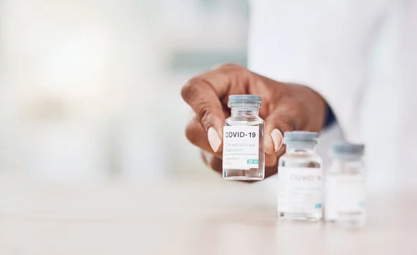 Closeup hand of african american woman doctor lining up bottles of the corona virus vaccine while working in her hospital office. Be safe during the pandemic outbreak. Stop the spread of covid 19.