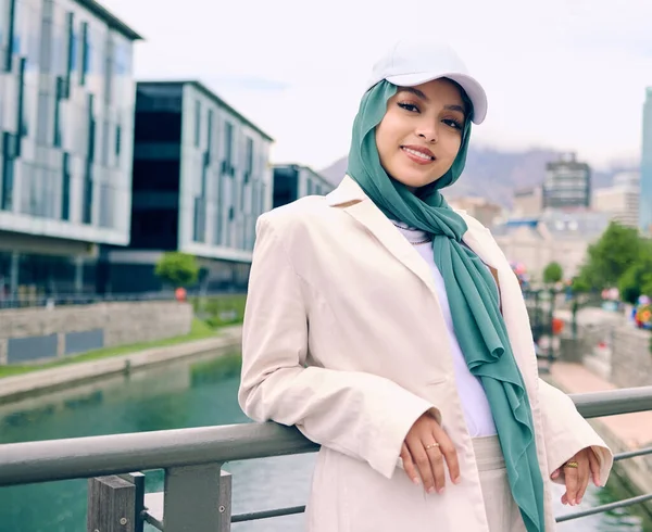 Beautiful young arab woman posing outdoors in a headscarf. Attractive female muslim wearing a hijab posing outside. Shes all about style and fashion. Mixed race woman looking confident and trendy.